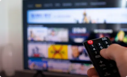 Person using a remote control to control a television.