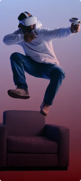 A man wearing a virtual reality headset jumping over a couch.
